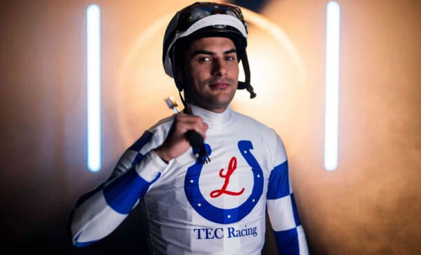 A jockey wearing white-and-blue racing silks.