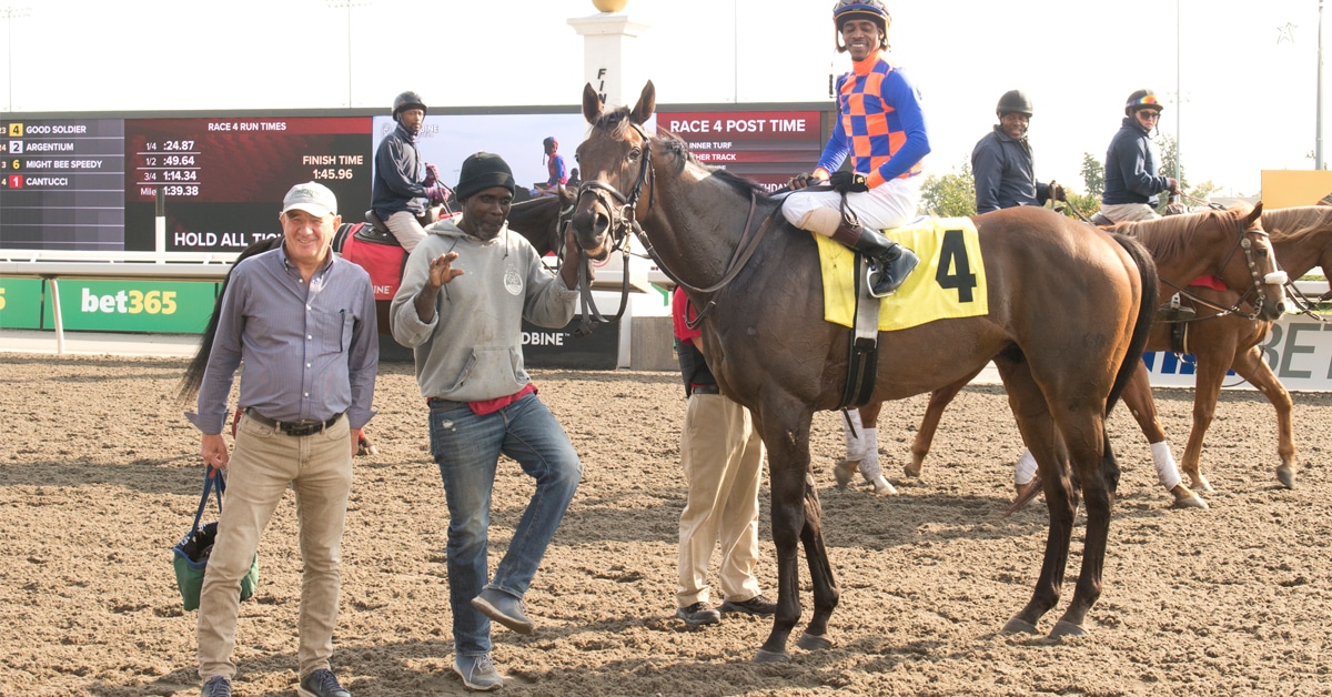 A groom dancing while holding a horse in the winners circle.