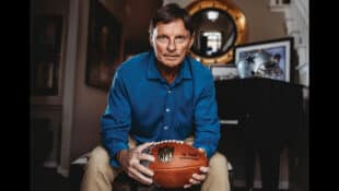 A man in a blue shirt holding a football.