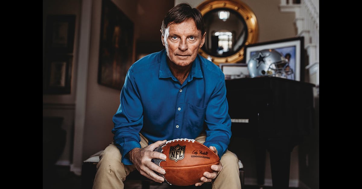 A man in a blue shirt holding a football.