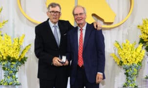 A man handing another man an award on stage.