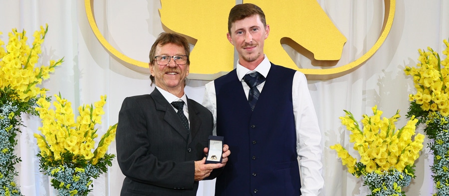 A former jockey being presented an award on stage.