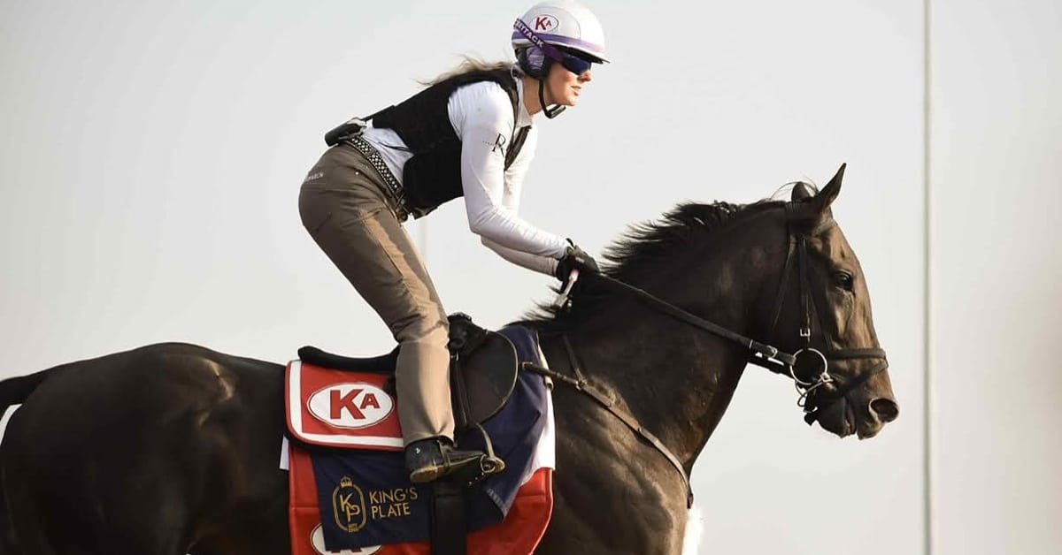 A woman excercizing a bay racehorse.