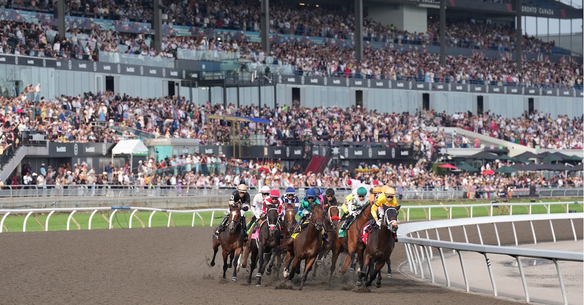 Horses racing at Woodbine in front of a packed grandstand.