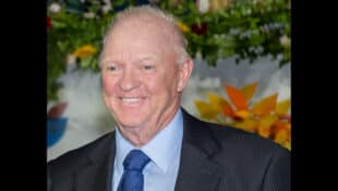 A headshot of a smiling, grey-haired man in a suit.