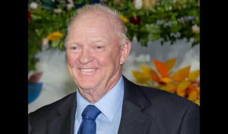 A headshot of a smiling, grey-haired man in a suit.