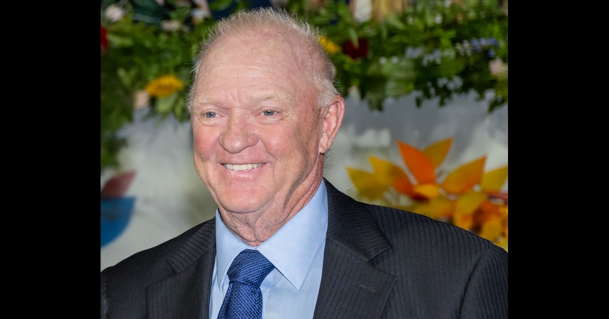 A headshot of a smiling, grey-haired man in a suit.