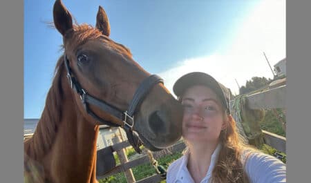 A young woman taking a selfie with a chestnut Thoroughbred.