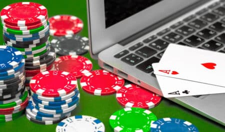 Poker chips, playing cards and a laptop.