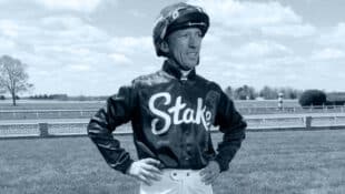 A jockey standing with hands on hips.