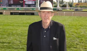 A man in a tan hat standing on the Woodbine turf course.