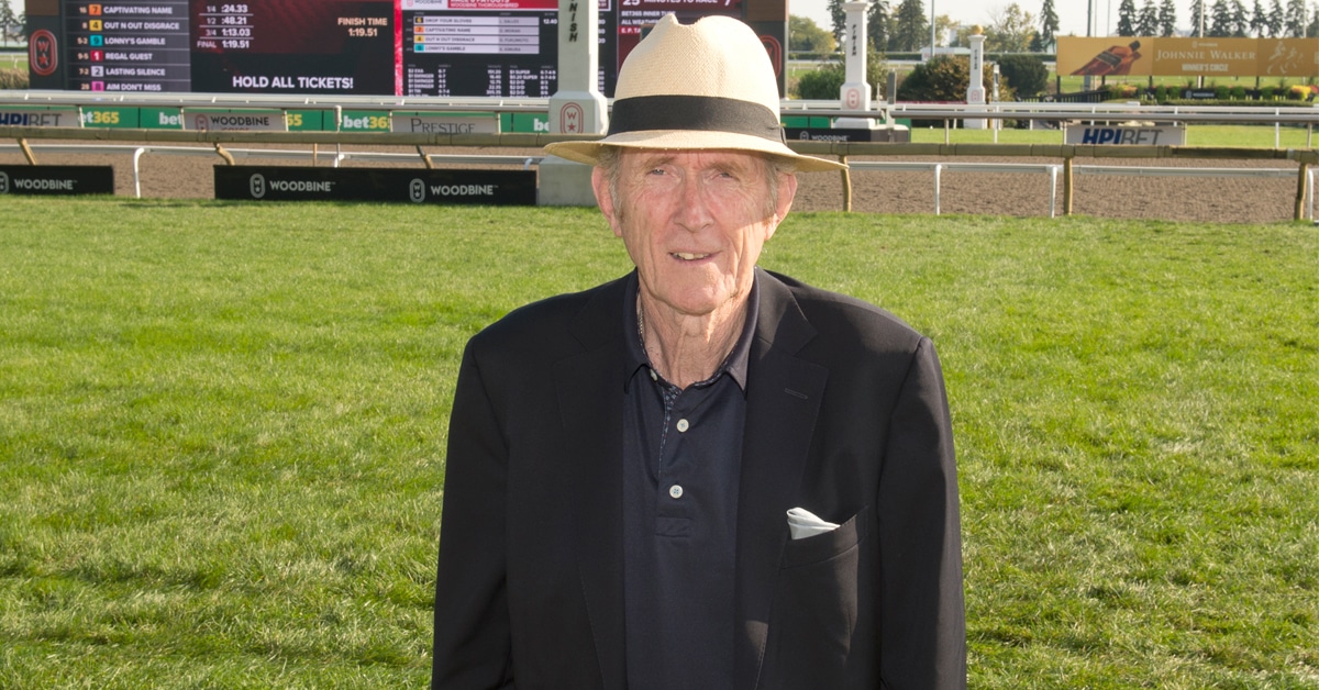 A man in a tan hat standing on the Woodbine turf course.