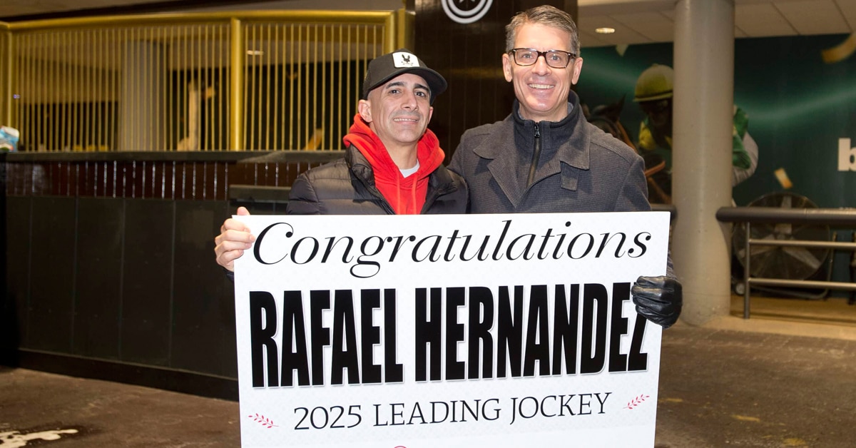 Two men in a barn holding up a sign.