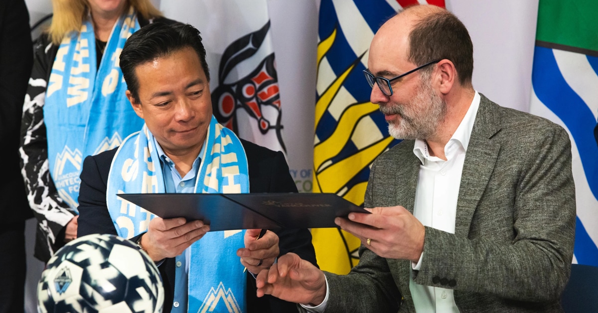 Two men signing some papers.