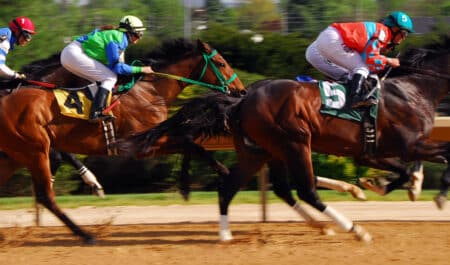 Horses racing on a dirt track.
