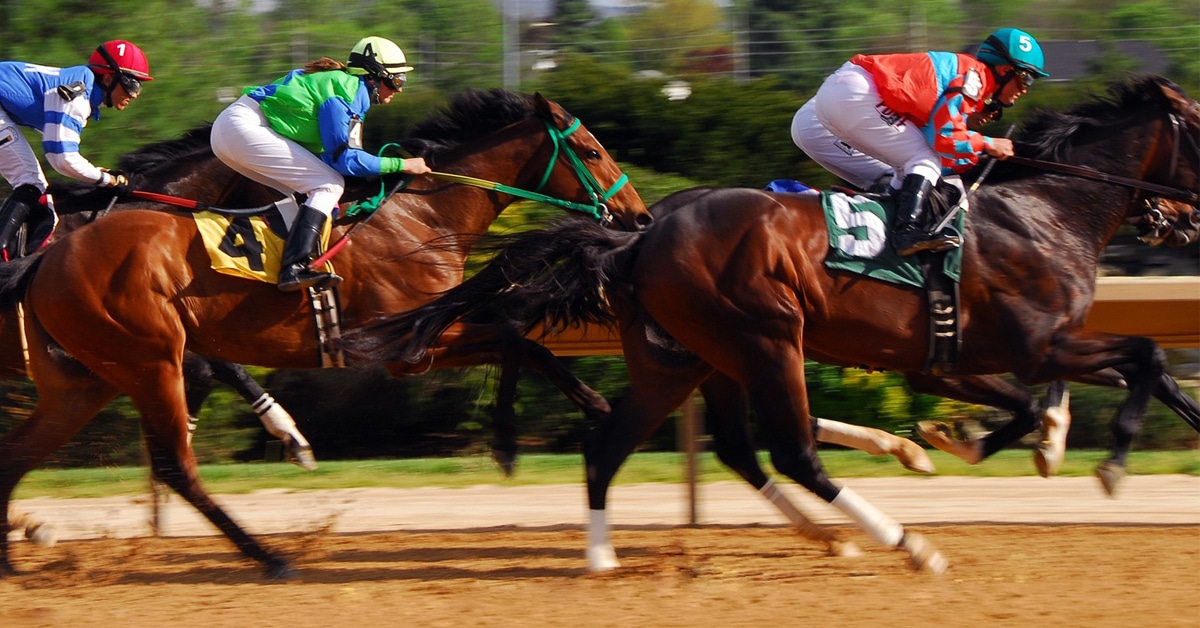 Horses racing on a dirt track.