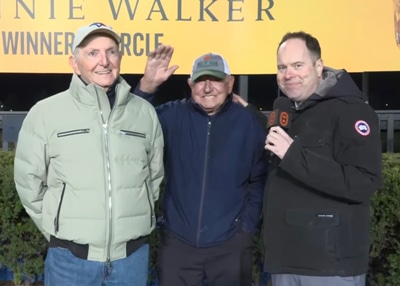 Three smiling men in the Woodbine winners circle.