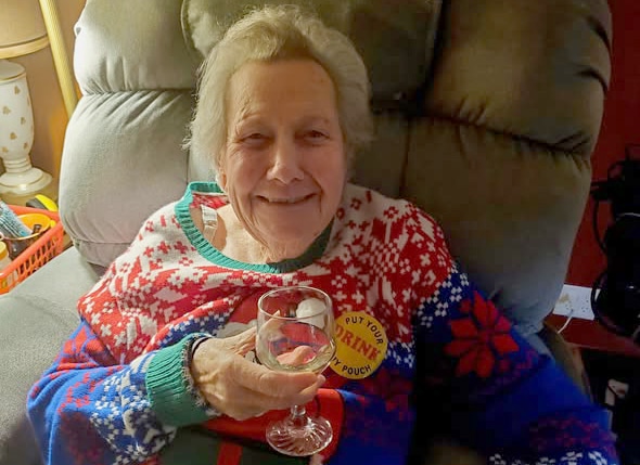 An elderly woman with a glass of wine.