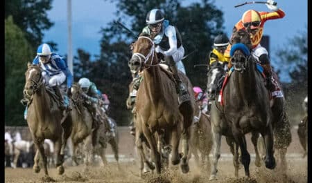 Head-on shot of horses racing at Churchill Downs.