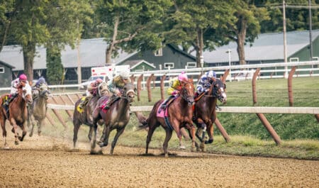 Horses racing on a dirt track.