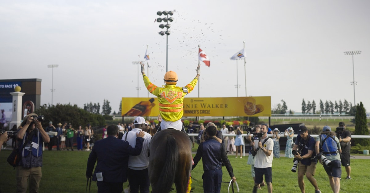 Back view of a celebrating jockey and horse entering the winners circle.