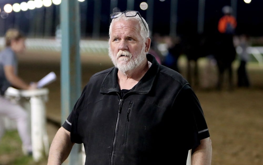 A man with a grey beard at the racetrack.