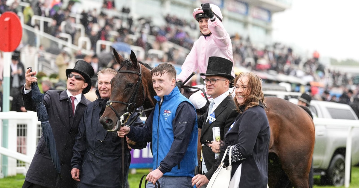 A group of people with a horse and jockey in the winners circle.