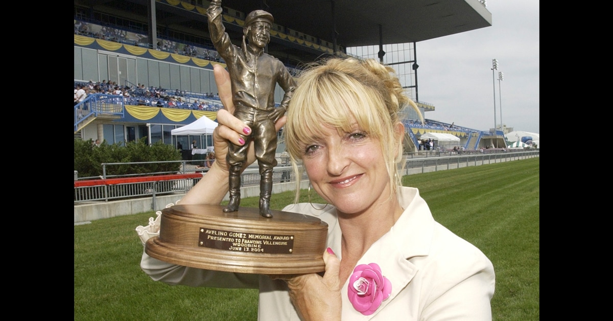 A woman holding up a trophy at the racetrack.