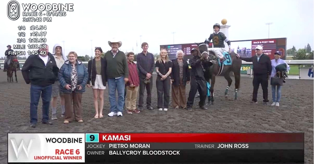 A group of people with a horse and jockey in a winning photo at the track.