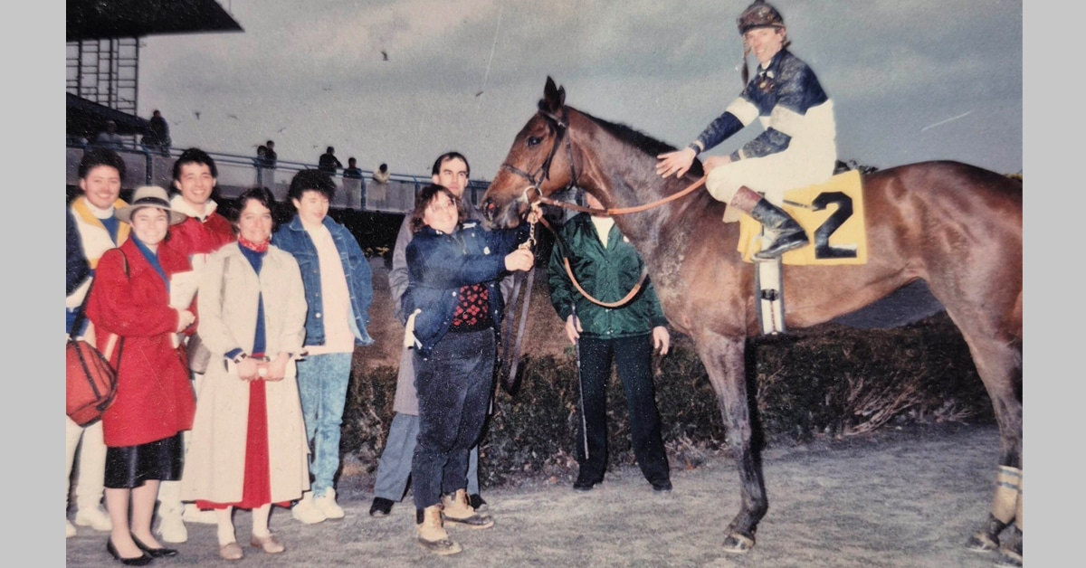 An old photo of a horse and group of people in the winners circle at Aqueduct.