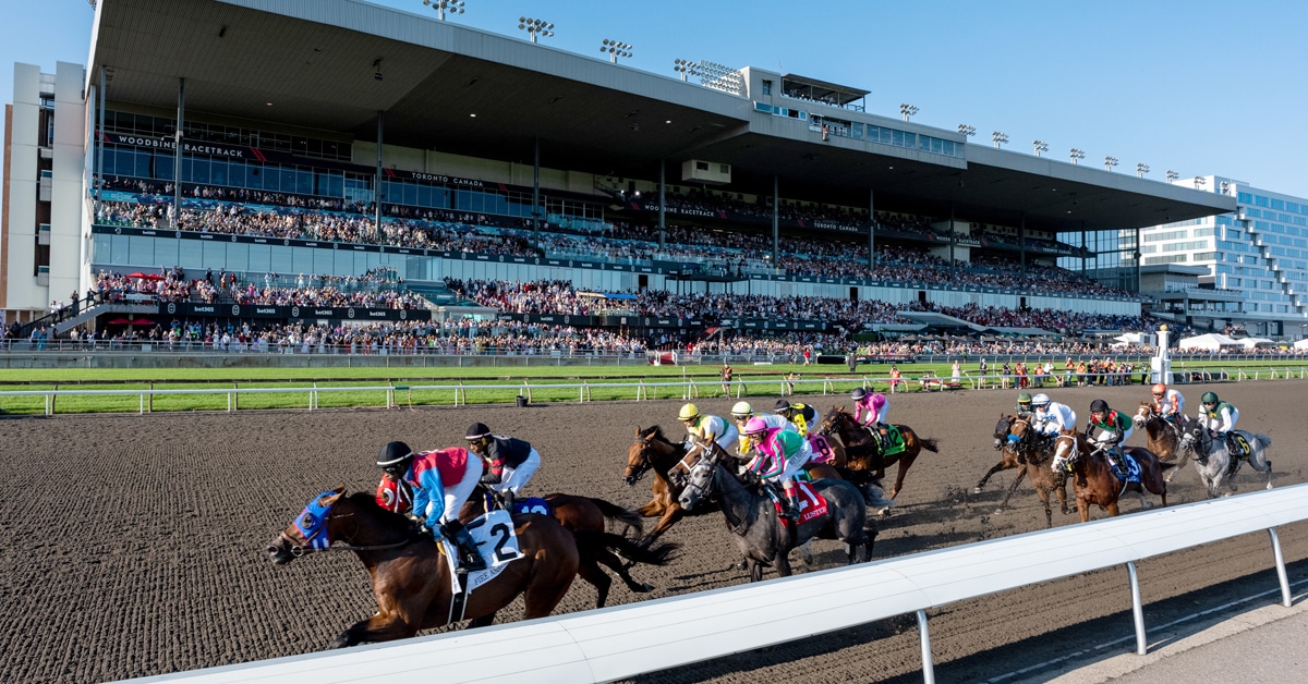 Horses racing in front of a packed grandstand at Woodbine.