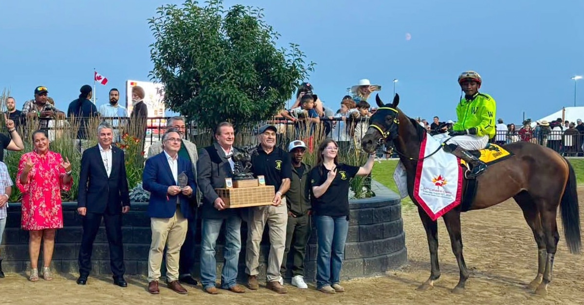A group of people with a horse and jockey in the winner's circle.