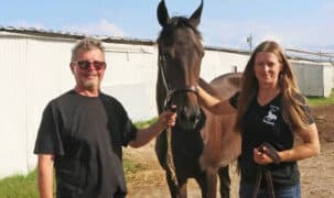 A man and a woman standing with a bay filly.