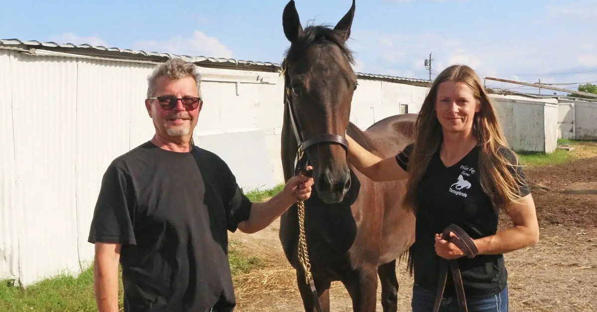 A man and a woman standing with a bay filly.