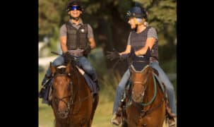 Two riders on racehorses, talking and laughing.