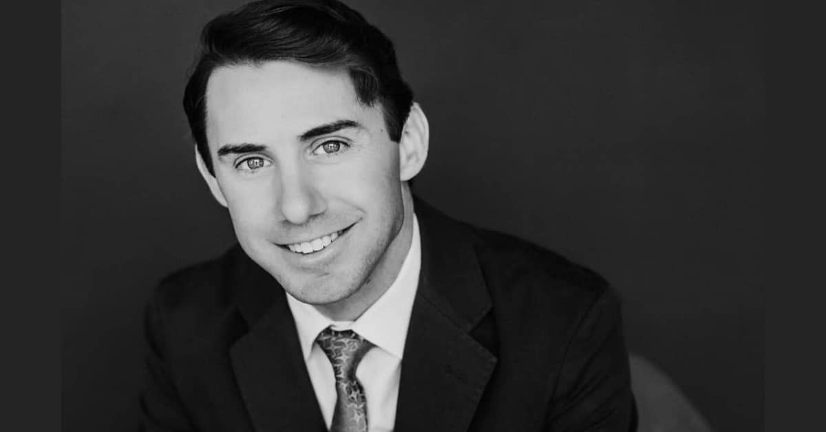 A black and white photo of a smiling man.