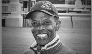 A black-and-white image of a black racehorse trainer.
