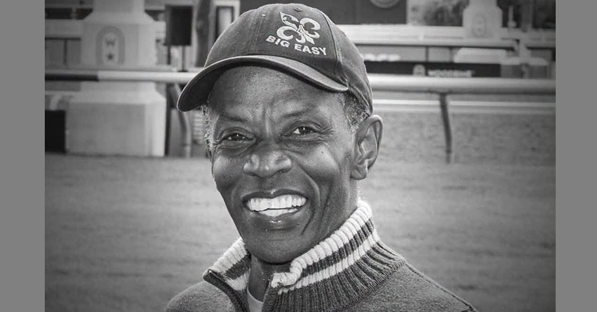 A black-and-white image of a black racehorse trainer.